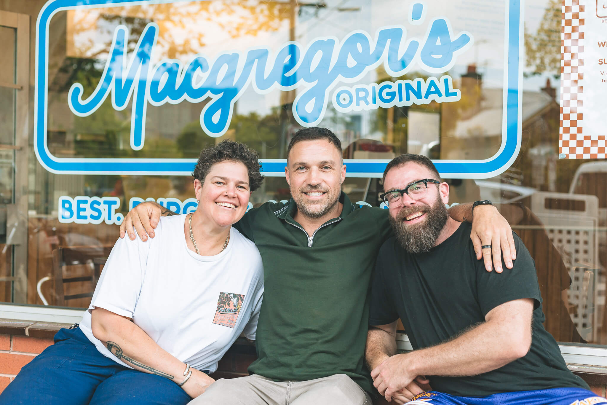 Three of the Macgregor's crew grinning in front of the shop window.